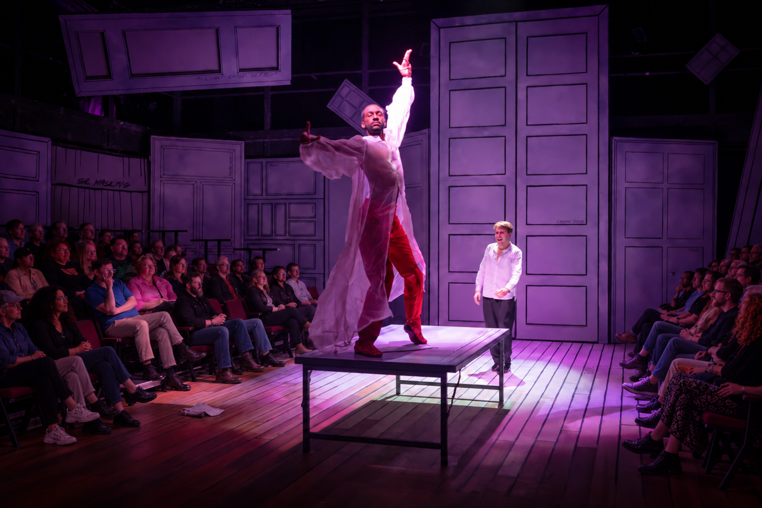 A performer reaches upward on a platform as the audience watches.