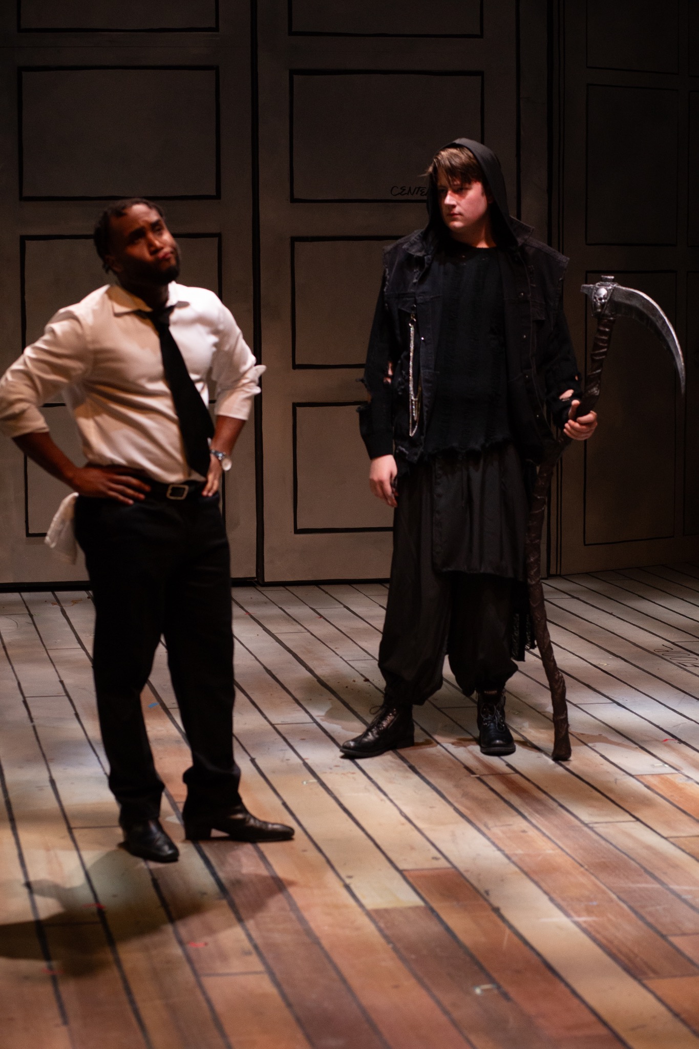 Two performers confront each other under a focused light.
