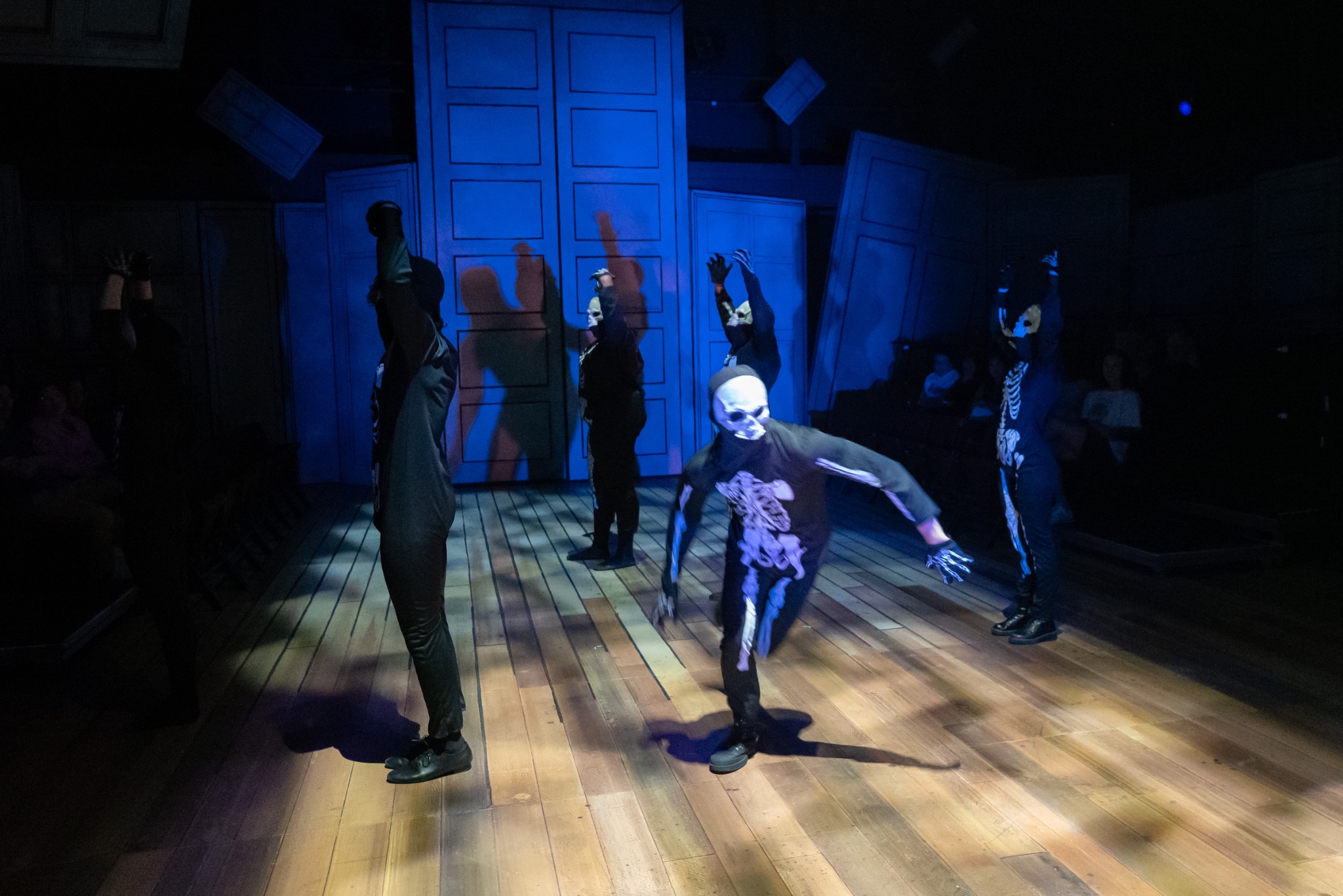 An ensemble moves through a cool blue wash.