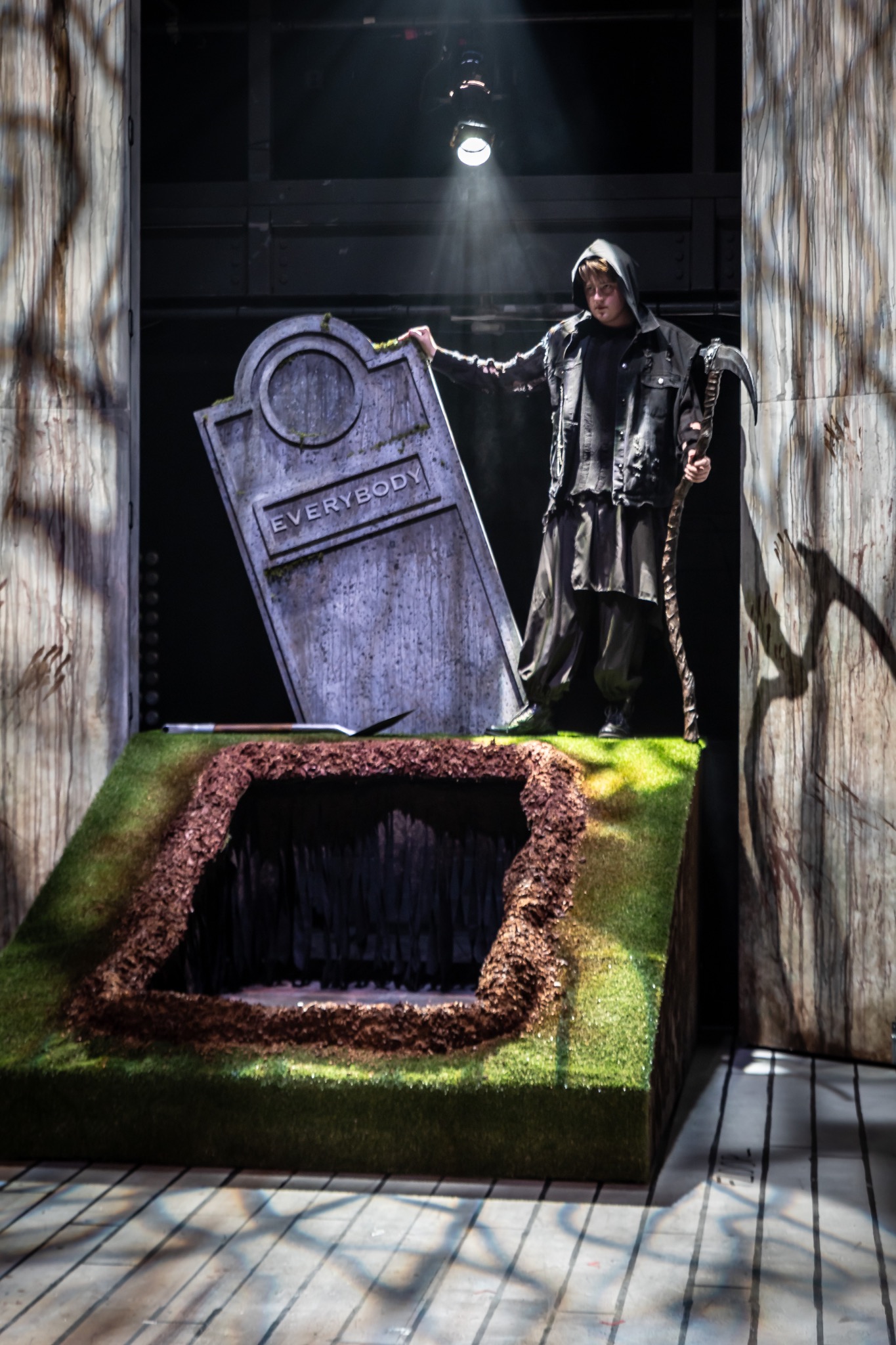A performer stands beside the revealed grave and headstone.