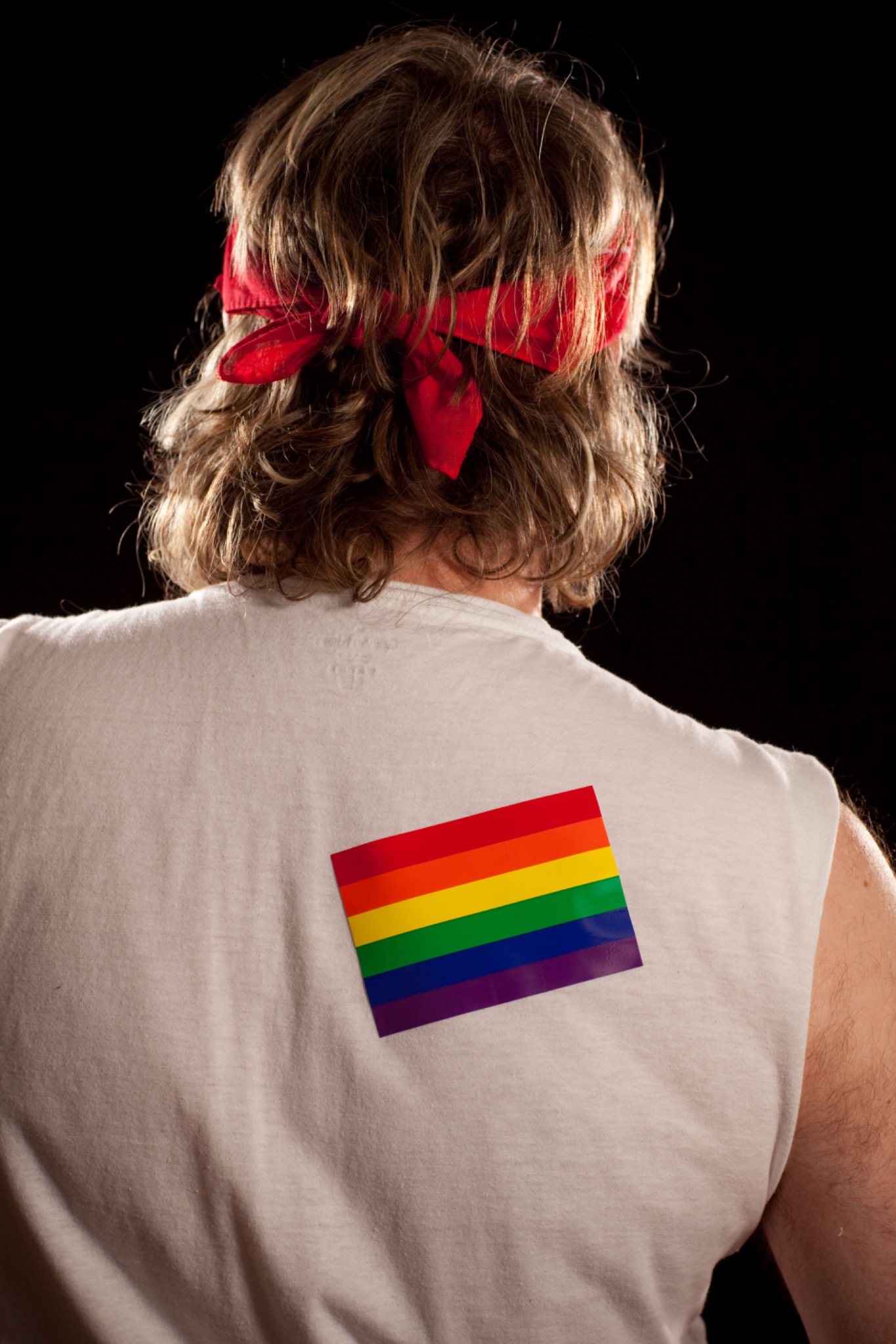 The performer seen from behind wearing a rainbow emblem on a white shirt