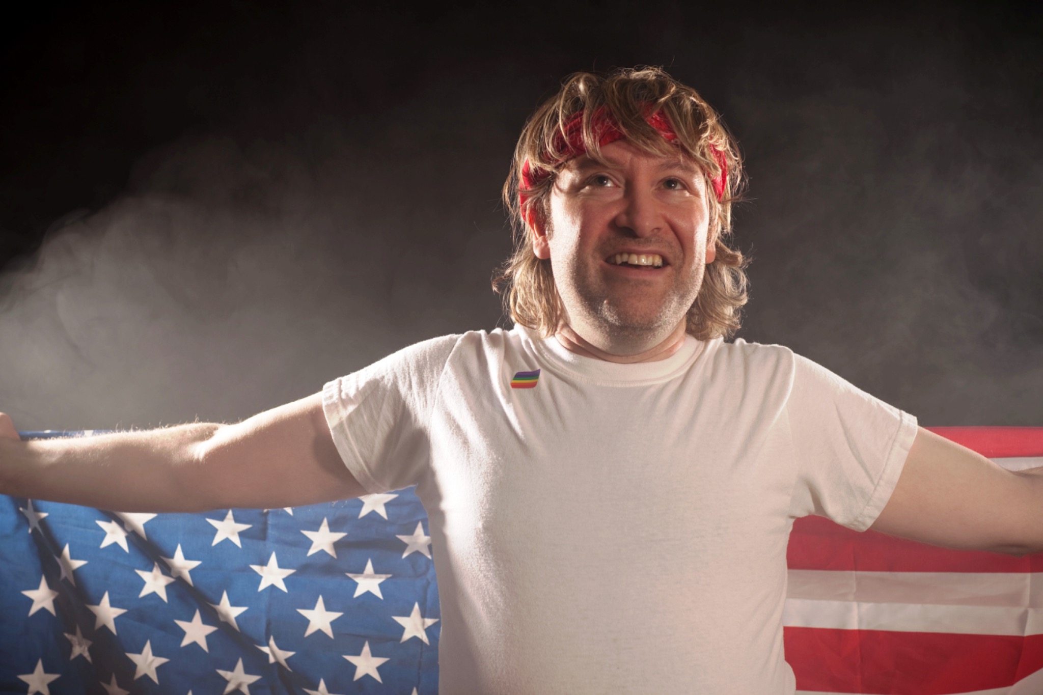 The performer opens his arms in front of an American flag